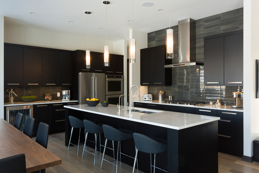 Example of a mid-sized trendy single-wall medium tone wood floor and brown floor open concept kitchen design in Other with a double-bowl sink, flat-panel cabinets, black cabinets, granite countertops, gray backsplash, ceramic backsplash, stainless steel appliances, an island and white countertops