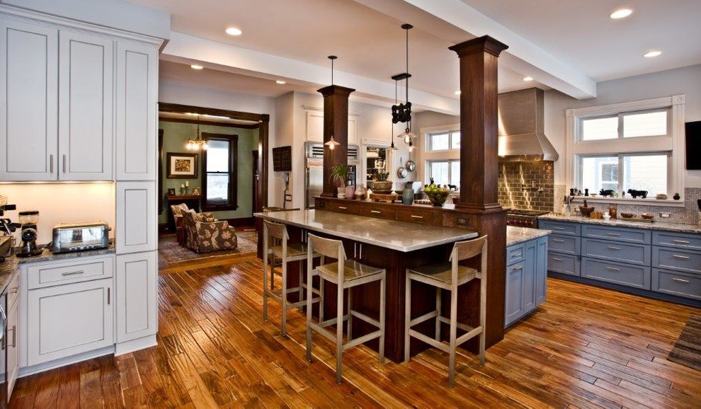 Inspiration för ett stort amerikanskt kök, med en undermonterad diskho, skåp i shakerstil, blå skåp, bänkskiva i akrylsten, stänkskydd med metallisk yta, stänkskydd i metallkakel, rostfria vitvaror, mellanmörkt trägolv, en köksö och brunt golv