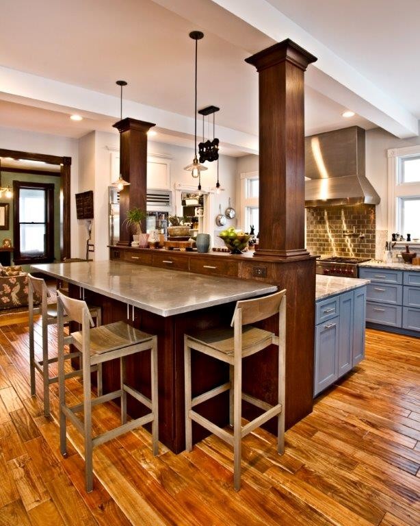 Inredning av ett amerikanskt stort kök, med en undermonterad diskho, skåp i shakerstil, blå skåp, bänkskiva i akrylsten, stänkskydd med metallisk yta, stänkskydd i metallkakel, rostfria vitvaror, mellanmörkt trägolv, en köksö och brunt golv