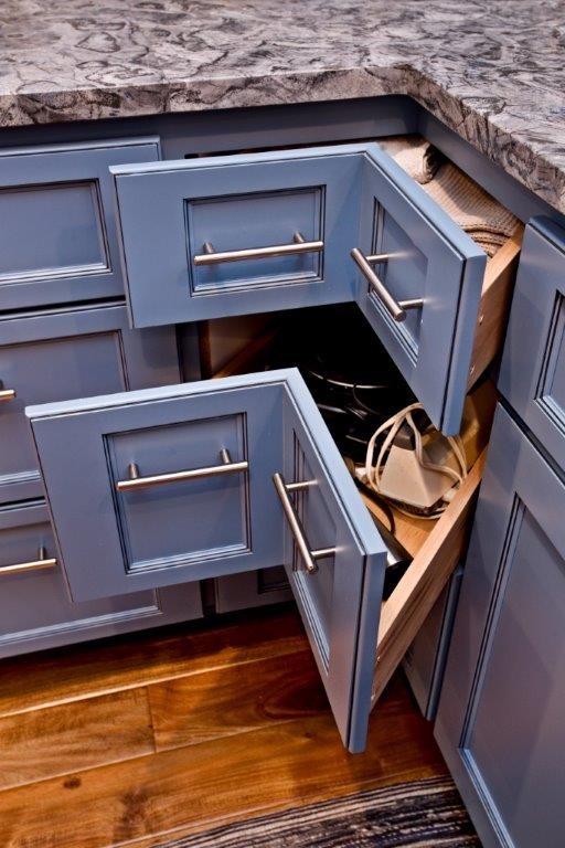 Amerikansk inredning av ett stort kök, med en undermonterad diskho, skåp i shakerstil, blå skåp, bänkskiva i akrylsten, stänkskydd med metallisk yta, stänkskydd i metallkakel, rostfria vitvaror, mellanmörkt trägolv, en köksö och brunt golv