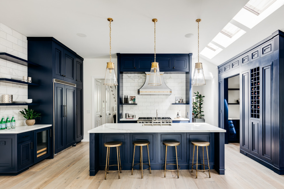 Photo of a traditional u-shaped kitchen in San Francisco with blue cabinets, a submerged sink, shaker cabinets, white splashback, metro tiled splashback, integrated appliances, light hardwood flooring, beige floors and white worktops.