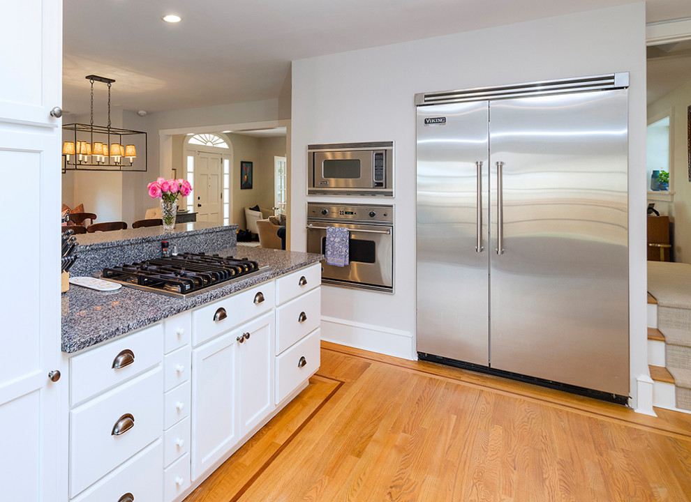 Exempel på ett mellanstort amerikanskt grå grått kök, med en undermonterad diskho, skåp i shakerstil, vita skåp, granitbänkskiva, rostfria vitvaror, mellanmörkt trägolv, en halv köksö och brunt golv