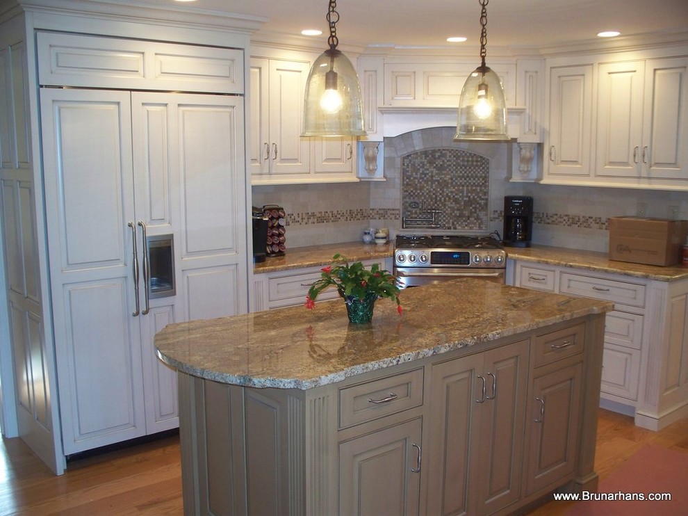 This is an example of an expansive traditional l-shaped enclosed kitchen in Boston with granite worktops, an island, beaded cabinets, distressed cabinets, beige splashback, metro tiled splashback, stainless steel appliances and medium hardwood flooring.
