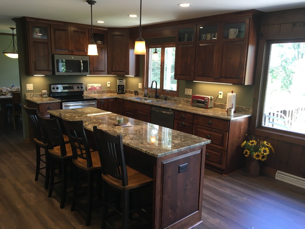 Large classic u-shaped open plan kitchen in Other with a submerged sink, raised-panel cabinets, dark wood cabinets, granite worktops, stainless steel appliances and an island.