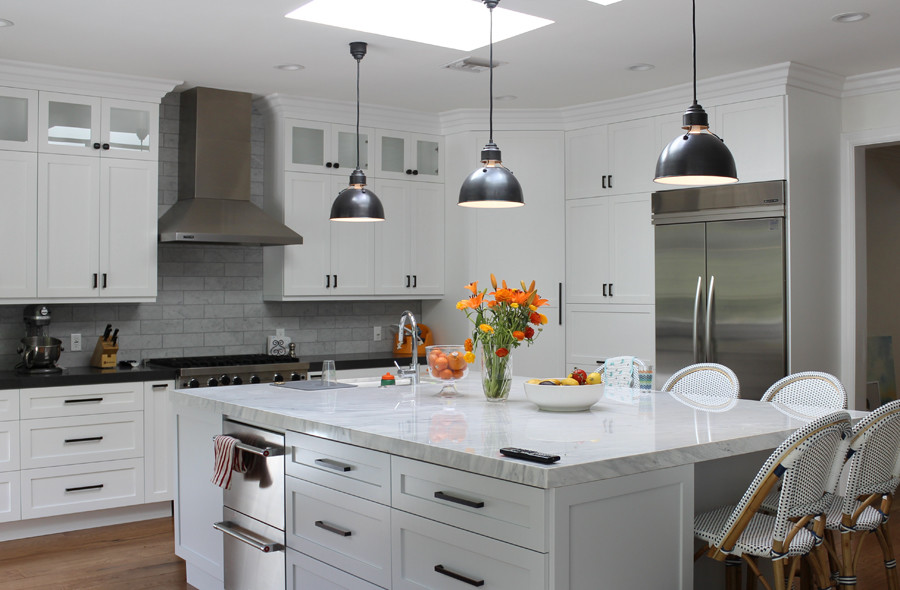 Inspiration for a large transitional u-shaped medium tone wood floor and brown floor eat-in kitchen remodel in Los Angeles with a farmhouse sink, marble countertops, gray backsplash, stone tile backsplash, stainless steel appliances, an island, gray countertops and white cabinets
