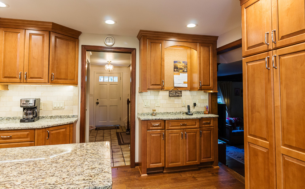 Bild på ett avskilt, stort vintage u-kök, med en undermonterad diskho, luckor med upphöjd panel, skåp i mellenmörkt trä, granitbänkskiva, beige stänkskydd, stänkskydd i stenkakel, rostfria vitvaror, mörkt trägolv, en köksö och brunt golv