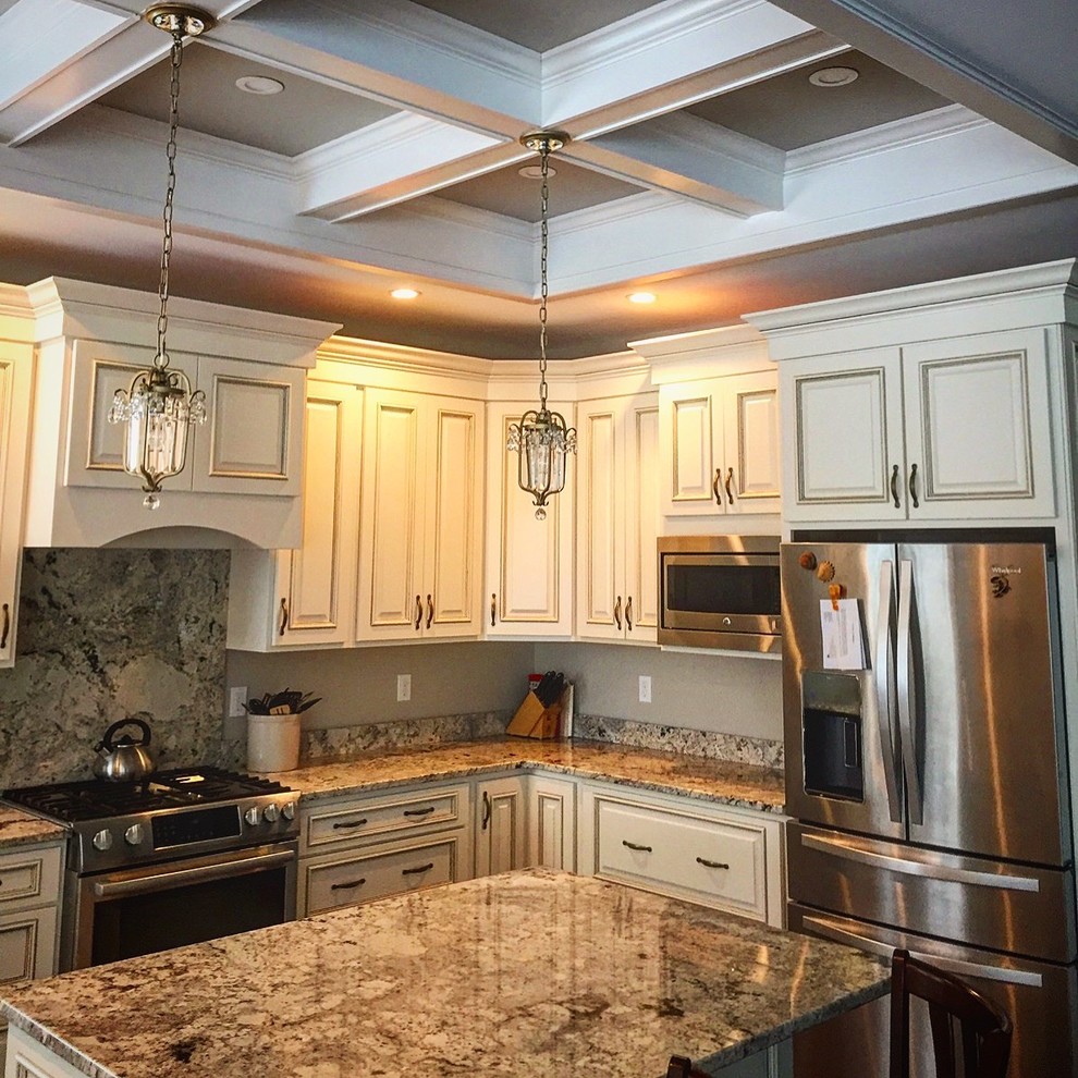 This is an example of a medium sized classic l-shaped enclosed kitchen in Portland Maine with a submerged sink, raised-panel cabinets, white cabinets, granite worktops, stainless steel appliances, an island, beige worktops, dark hardwood flooring, brown floors, beige splashback and stone slab splashback.