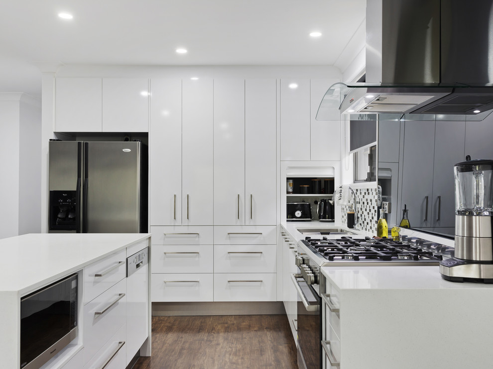 Esempio di una cucina minimalista di medie dimensioni con ante lisce, ante bianche, top in laminato, paraspruzzi nero, paraspruzzi con lastra di vetro, elettrodomestici in acciaio inossidabile e top bianco