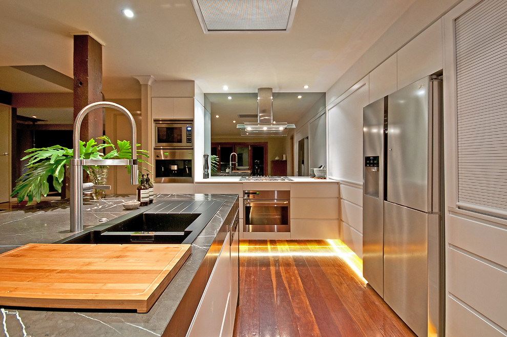 Zweizeilige, Große Moderne Wohnküche mit Einbauwaschbecken, beigen Schränken, Marmor-Arbeitsplatte, Küchengeräten aus Edelstahl, braunem Holzboden und Kücheninsel in Gold Coast - Tweed
