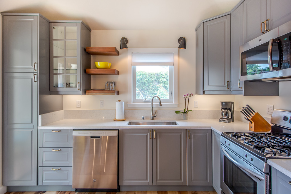 Inspiration for a small beach style l-shaped kitchen/diner in San Francisco with a single-bowl sink, grey cabinets, white splashback, stone slab splashback, stainless steel appliances, medium hardwood flooring, no island, flat-panel cabinets and engineered stone countertops.