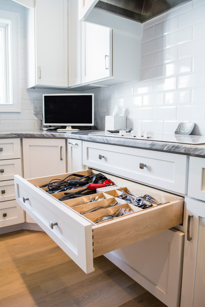 Klassisk inredning av ett mellanstort kök, med en undermonterad diskho, skåp i shakerstil, vita skåp, marmorbänkskiva, vitt stänkskydd, stänkskydd i tunnelbanekakel, rostfria vitvaror, ljust trägolv och en köksö