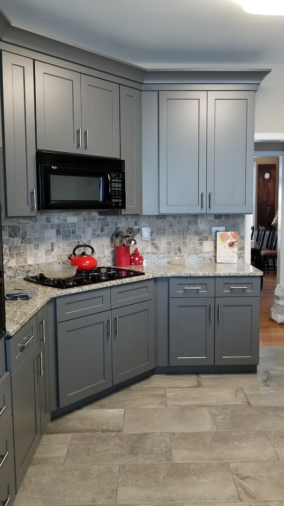 Mid-sized transitional u-shaped porcelain tile and gray floor enclosed kitchen photo in Atlanta with an undermount sink, shaker cabinets, gray cabinets, granite countertops, multicolored backsplash, travertine backsplash, black appliances and a peninsula