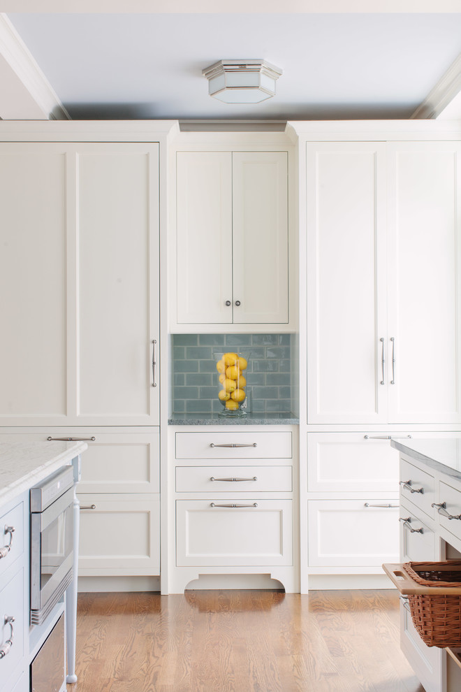 Example of a large classic l-shaped medium tone wood floor open concept kitchen design in Chicago with an undermount sink, shaker cabinets, white cabinets, granite countertops, blue backsplash, subway tile backsplash, stainless steel appliances and an island