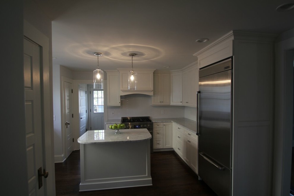 Modelo de cocina actual de tamaño medio con encimera de mármol, electrodomésticos de acero inoxidable y suelo de madera oscura