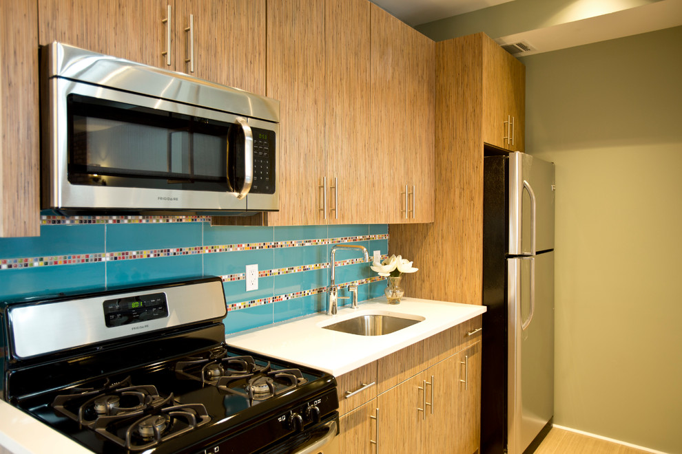 Small minimalist galley ceramic tile and brown floor eat-in kitchen photo in New York with an undermount sink, flat-panel cabinets, medium tone wood cabinets, quartz countertops, multicolored backsplash, ceramic backsplash, stainless steel appliances and a peninsula