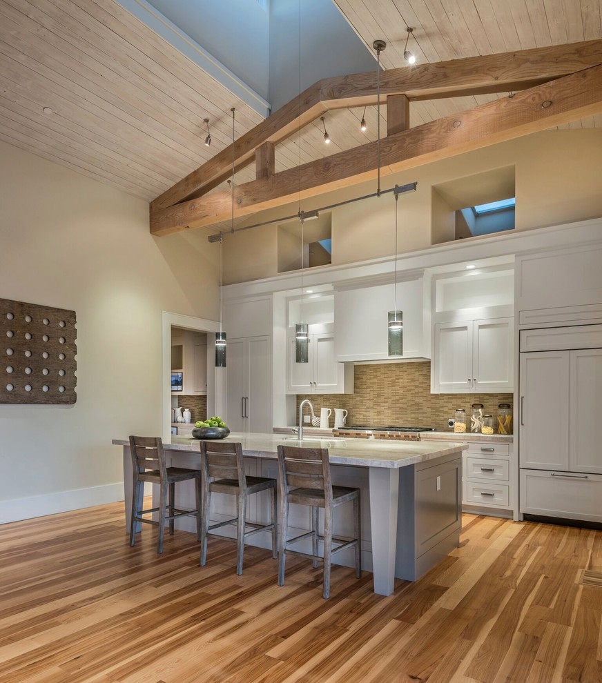 This is an example of a country galley kitchen in San Francisco with a submerged sink, shaker cabinets, white cabinets, brown splashback, integrated appliances, medium hardwood flooring, an island and brown floors.