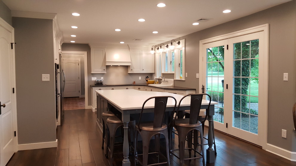 Design ideas for a medium sized eclectic l-shaped kitchen/diner in Philadelphia with a belfast sink, beaded cabinets, white cabinets, granite worktops, stainless steel appliances, dark hardwood flooring and an island.
