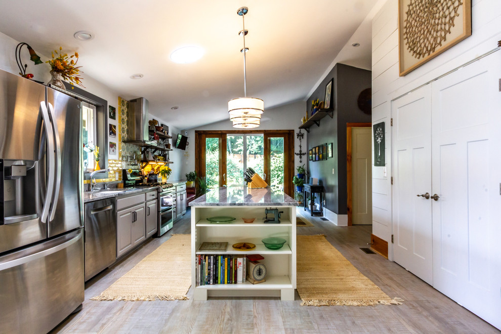 Idéer för att renovera ett mellanstort eklektiskt grå linjärt grått kök, med en nedsänkt diskho, luckor med upphöjd panel, grå skåp, granitbänkskiva, gult stänkskydd, stänkskydd i keramik, rostfria vitvaror, laminatgolv, en köksö och grått golv