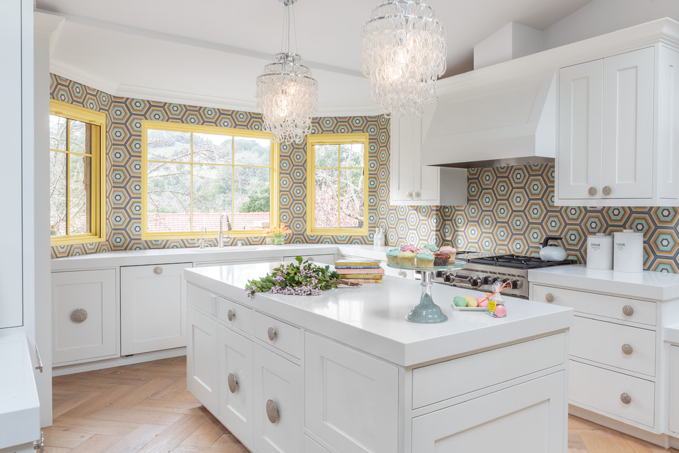Mid-sized transitional l-shaped medium tone wood floor enclosed kitchen photo in San Francisco with a single-bowl sink, shaker cabinets, white cabinets, quartz countertops, multicolored backsplash, stainless steel appliances and an island