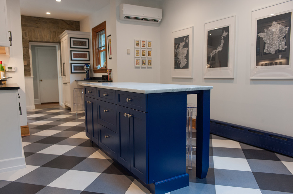 Foto på ett avskilt eklektiskt kök, med en rustik diskho, vitt stänkskydd, korkgolv, en köksö, blå skåp, marmorbänkskiva, rostfria vitvaror och flerfärgat golv