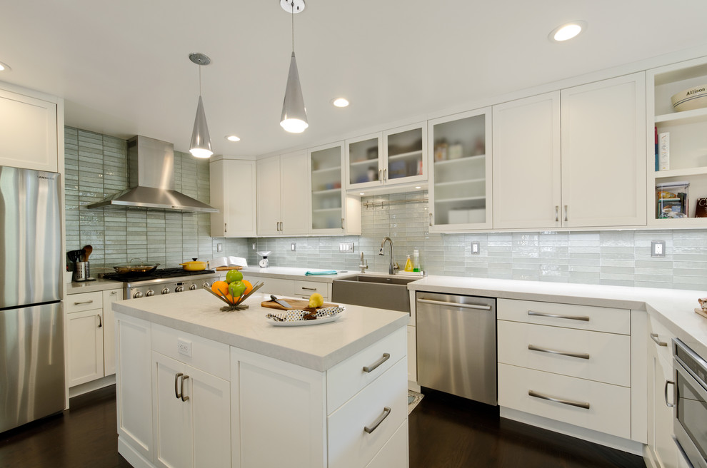 Foto på ett funkis vit u-kök, med en rustik diskho, skåp i shakerstil, vita skåp, grått stänkskydd, stänkskydd i glaskakel, rostfria vitvaror, mörkt trägolv, en köksö och brunt golv