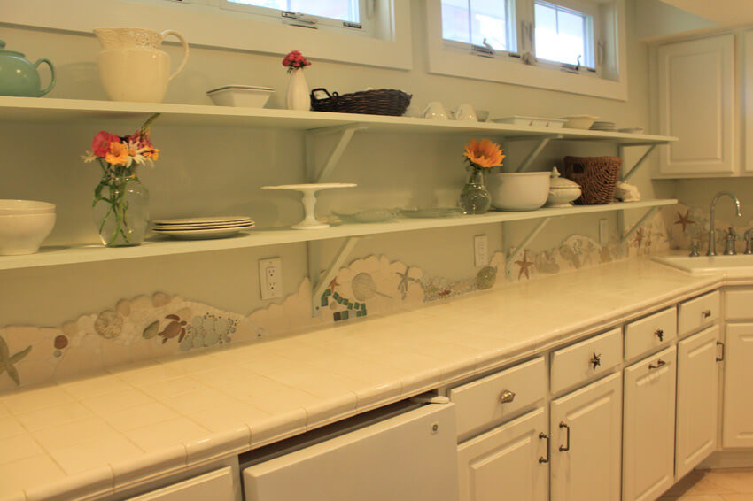 ワシントンD.C.にあるお手頃価格の小さなエクレクティックスタイルのおしゃれなII型キッチン (シングルシンク、レイズドパネル扉のキャビネット、白いキャビネット、タイルカウンター、マルチカラーのキッチンパネル、石タイルのキッチンパネル、白い調理設備、ライムストーンの床、アイランドなし) の写真