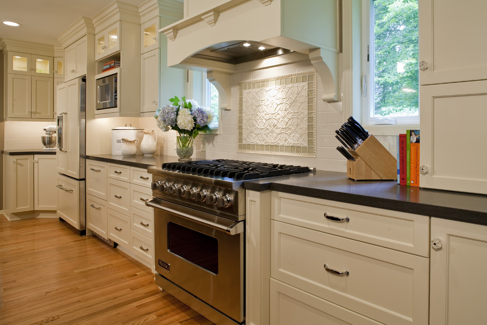 Exempel på ett stort klassiskt kök, med en undermonterad diskho, luckor med infälld panel, vita skåp, bänkskiva i kvarts, beige stänkskydd, stänkskydd i porslinskakel, rostfria vitvaror, mellanmörkt trägolv och en köksö