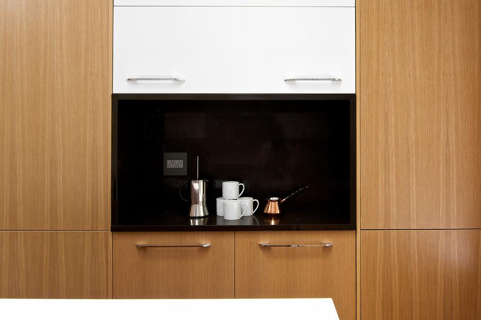Example of a small minimalist galley light wood floor and brown floor enclosed kitchen design in Seattle with a single-bowl sink, flat-panel cabinets, light wood cabinets, quartz countertops, white backsplash, ceramic backsplash, stainless steel appliances and an island