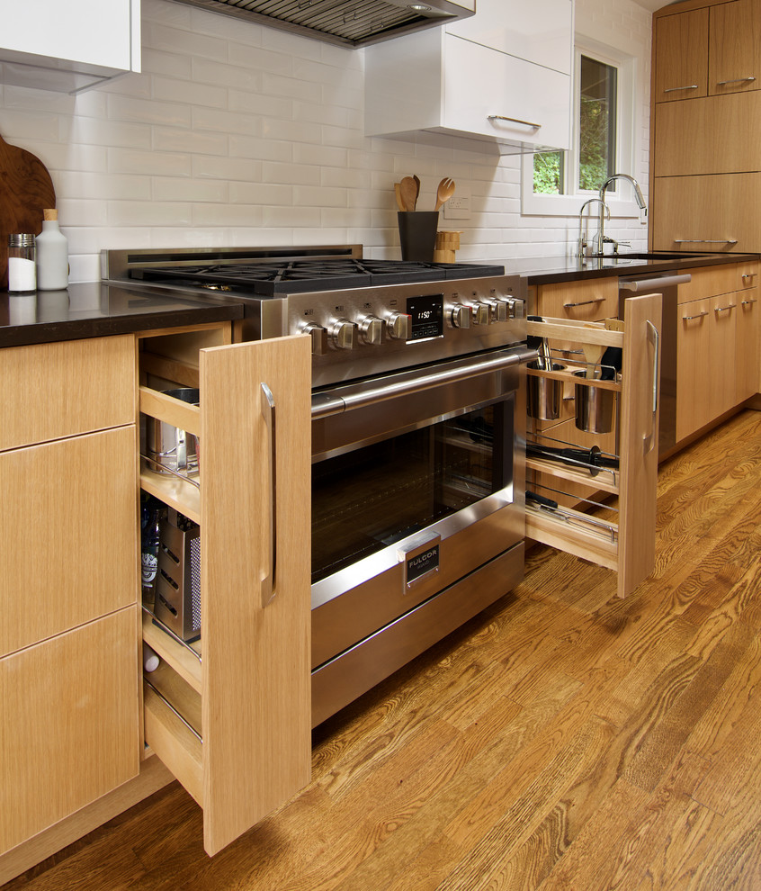 Inspiration for a small modern l-shaped light wood floor and brown floor enclosed kitchen remodel in Seattle with a single-bowl sink, flat-panel cabinets, light wood cabinets, quartz countertops, white backsplash, ceramic backsplash, stainless steel appliances and an island