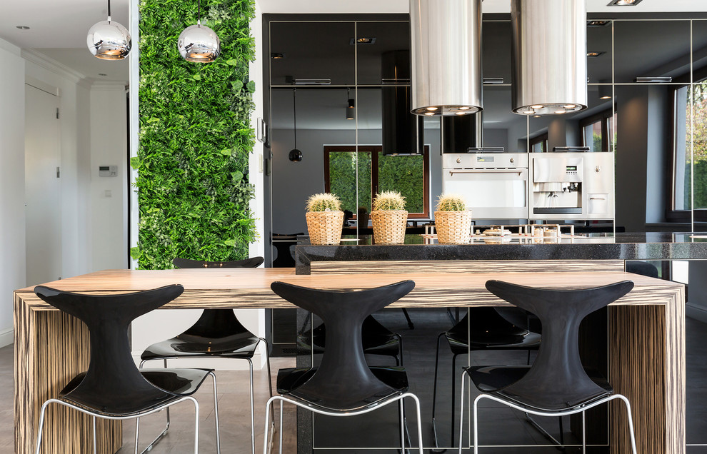 Trendy galley multicolored floor kitchen photo in Los Angeles with flat-panel cabinets, black cabinets, stainless steel appliances, an island and black countertops