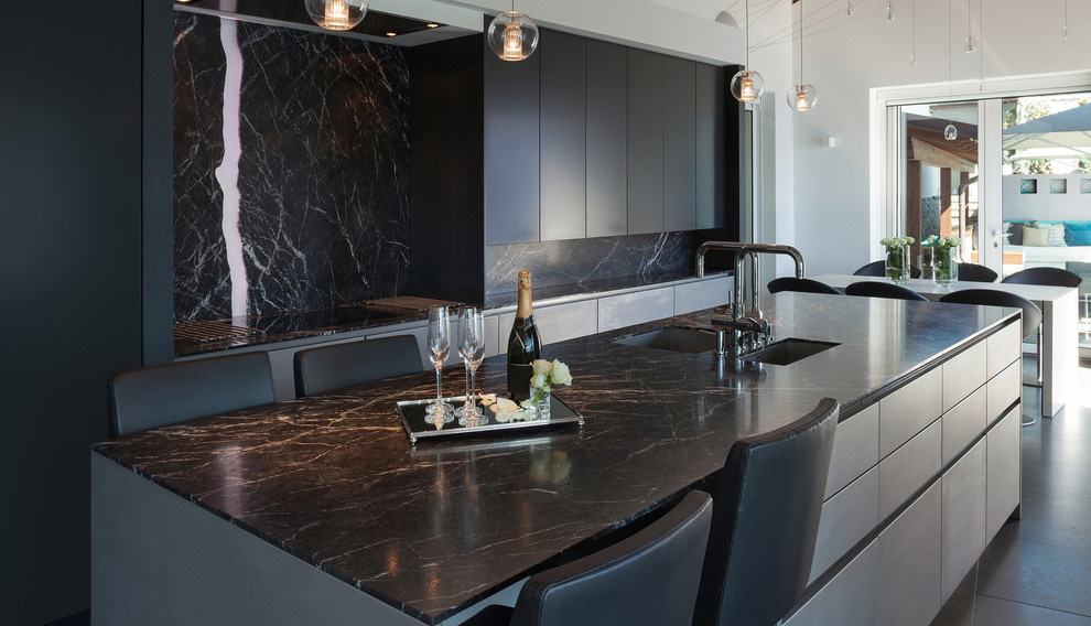 Cette photo montre une cuisine moderne de taille moyenne avec un placard à porte plane, une crédence noire, une crédence en marbre et îlot.