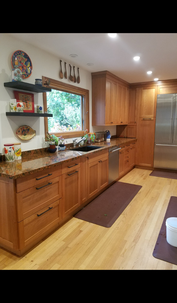 Mid-sized eclectic u-shaped light wood floor and yellow floor open concept kitchen photo in Los Angeles with an undermount sink, shaker cabinets, medium tone wood cabinets, quartz countertops, stainless steel appliances and a peninsula