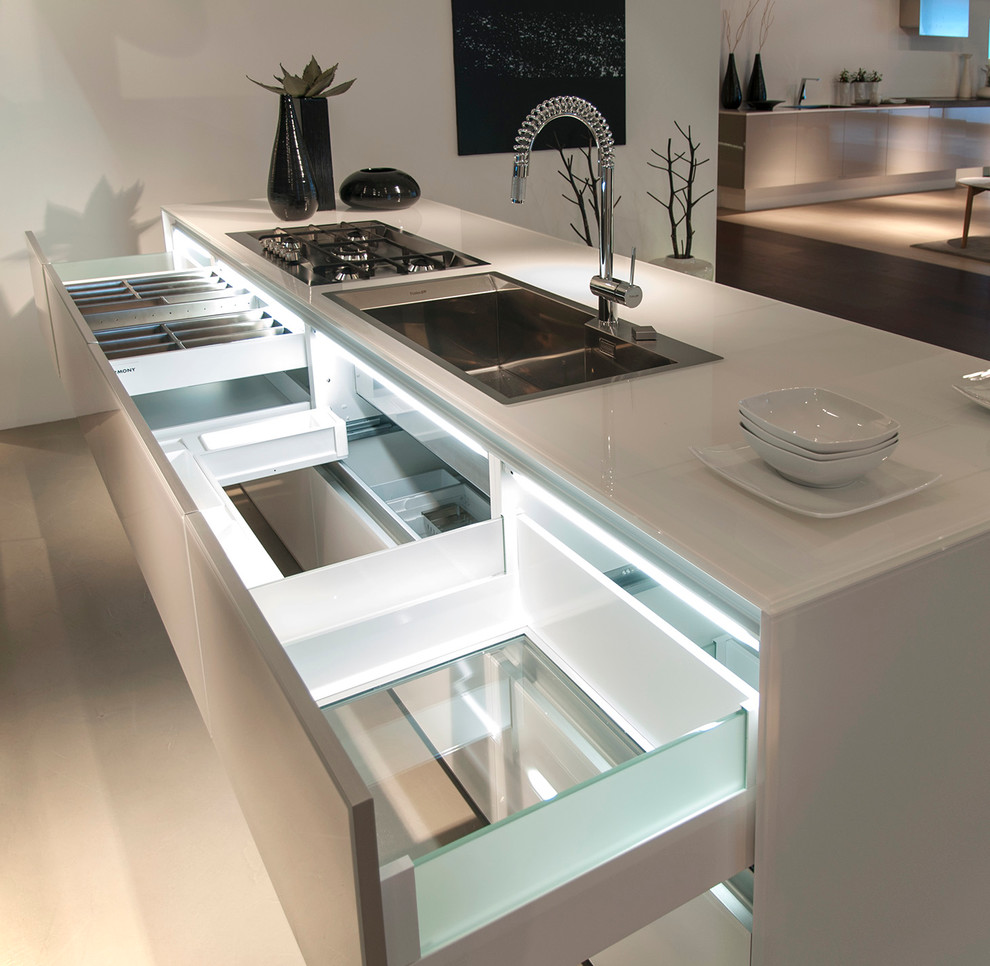 This is an example of a medium sized modern kitchen/diner in Orange County with a built-in sink, flat-panel cabinets, white cabinets, stainless steel appliances, an island, glass worktops, concrete flooring, beige floors and white worktops.