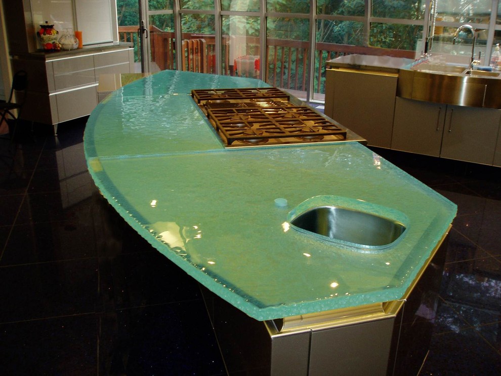 Cette image montre une cuisine américaine minimaliste avec un évier encastré, un plan de travail en verre et un plan de travail turquoise.