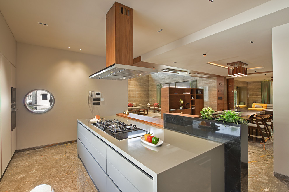 Стильный дизайн: кухня-гостиная в восточном стиле с плоскими фасадами, серыми фасадами, черной техникой, коричневым полом и серой столешницей - последний тренд