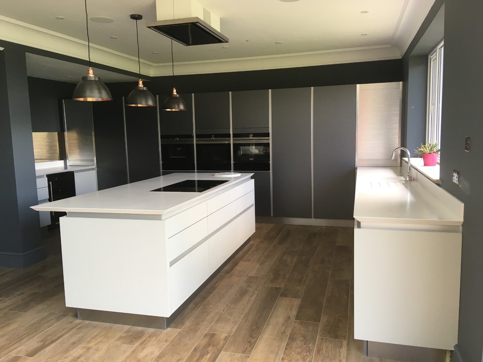 Design ideas for a large contemporary u-shaped kitchen in Oxfordshire with flat-panel cabinets, glass sheet splashback, integrated appliances, an island, brown floors and white worktops.