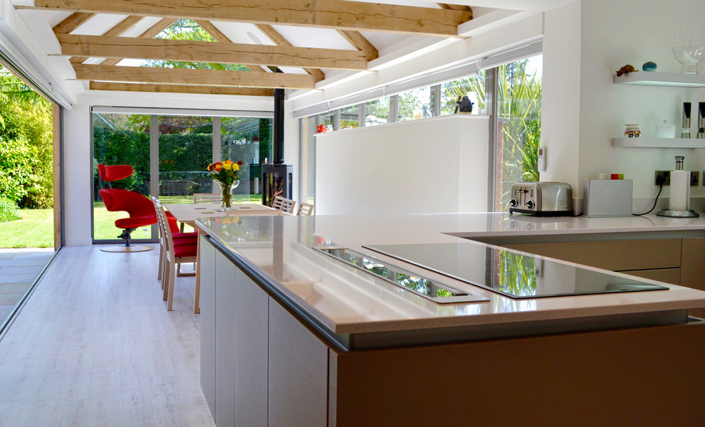 This is an example of a medium sized contemporary u-shaped kitchen/diner in West Midlands with quartz worktops, stainless steel appliances, vinyl flooring, no island and flat-panel cabinets.