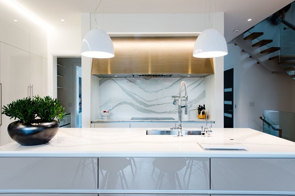 Photo of a medium sized modern l-shaped kitchen/diner in Toronto with a submerged sink, flat-panel cabinets, white cabinets, engineered stone countertops, white splashback, stainless steel appliances, an island and brown floors.