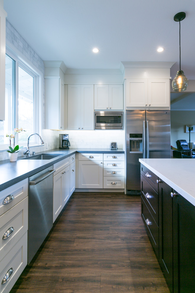 Mid-sized transitional l-shaped dark wood floor open concept kitchen photo in San Francisco with an undermount sink, shaker cabinets, white cabinets, solid surface countertops, gray backsplash, marble backsplash, stainless steel appliances and an island