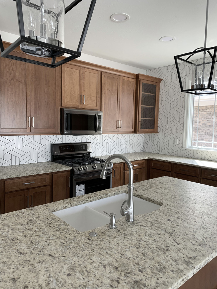 Example of a large transitional l-shaped eat-in kitchen design in Other with an undermount sink, shaker cabinets, medium tone wood cabinets, granite countertops, white backsplash, ceramic backsplash, stainless steel appliances, an island and multicolored countertops