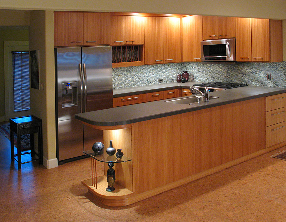 Foto på ett litet funkis kök, med en undermonterad diskho, släta luckor, skåp i mellenmörkt trä, kaklad bänkskiva, grönt stänkskydd, stänkskydd i glaskakel, rostfria vitvaror och korkgolv