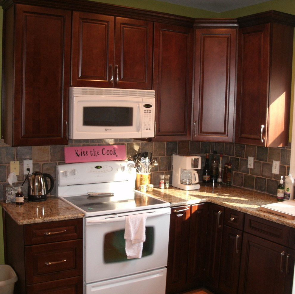 Immagine di una cucina stile rurale con ante con riquadro incassato, ante in legno scuro, top in granito, paraspruzzi multicolore e elettrodomestici bianchi