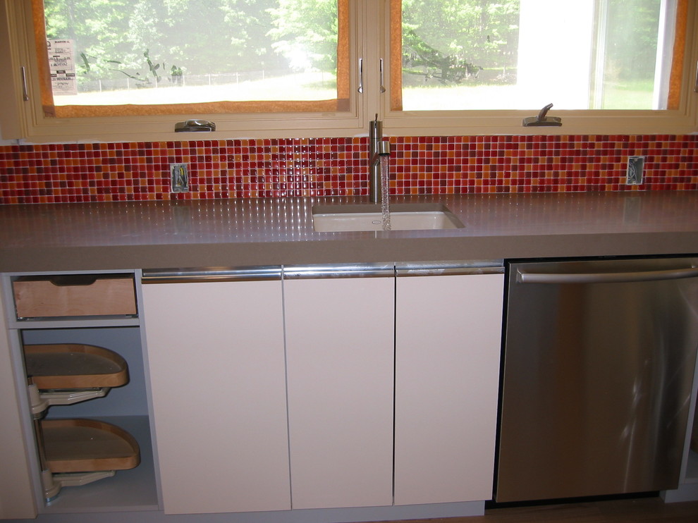 Modern inredning av ett litet kök, med en halv köksö, släta luckor, vita skåp, bänkskiva i koppar, flerfärgad stänkskydd, stänkskydd i glaskakel, rostfria vitvaror, en undermonterad diskho och ljust trägolv