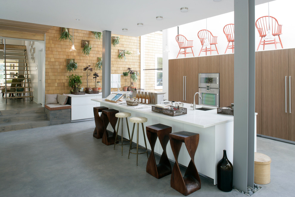 This is an example of a large bohemian single-wall kitchen/diner in Vancouver with a submerged sink, flat-panel cabinets, medium wood cabinets, stainless steel appliances, concrete flooring and an island.