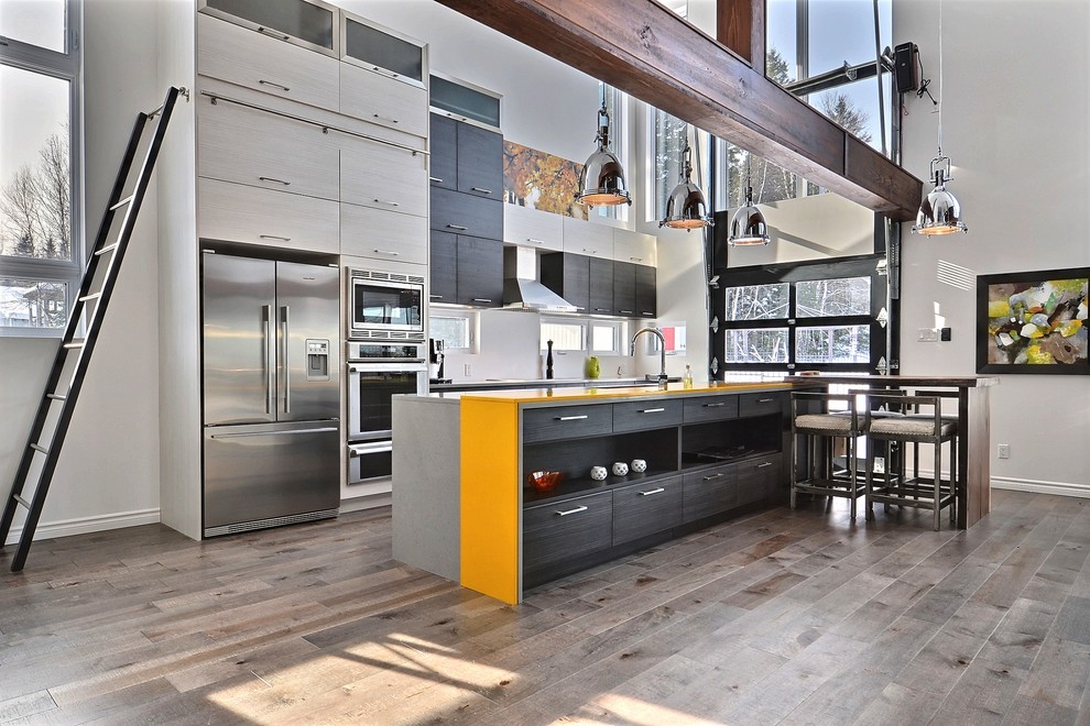 Offene, Zweizeilige, Mittelgroße Moderne Küche mit flächenbündigen Schrankfronten, dunklen Holzschränken, Küchenrückwand in Weiß, Küchengeräten aus Edelstahl, braunem Holzboden und Kücheninsel in Montreal