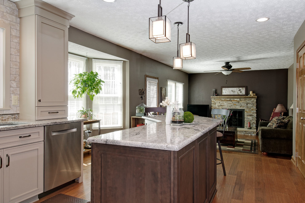 Eat-in kitchen - mid-sized traditional l-shaped medium tone wood floor eat-in kitchen idea in Columbus with an undermount sink, recessed-panel cabinets, beige cabinets, granite countertops, beige backsplash, ceramic backsplash, stainless steel appliances and an island