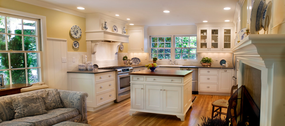 Mid-sized elegant u-shaped medium tone wood floor open concept kitchen photo in Portland with an undermount sink, beaded inset cabinets, white cabinets, soapstone countertops, white backsplash, ceramic backsplash, stainless steel appliances and an island