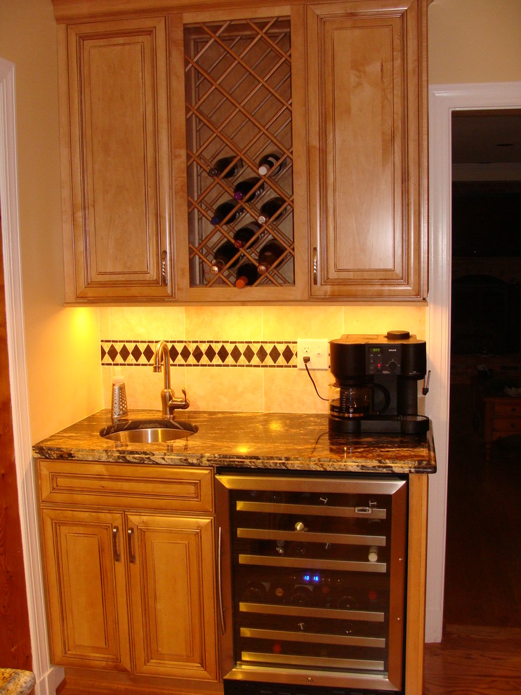 This is an example of a medium sized classic l-shaped kitchen pantry in DC Metro with a submerged sink, raised-panel cabinets, light wood cabinets, granite worktops, white splashback, ceramic splashback, stainless steel appliances, light hardwood flooring and an island.