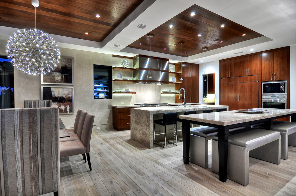 Diseño de cocina comedor contemporánea con armarios con paneles lisos, puertas de armario de madera en tonos medios, electrodomésticos con paneles y suelo laminado