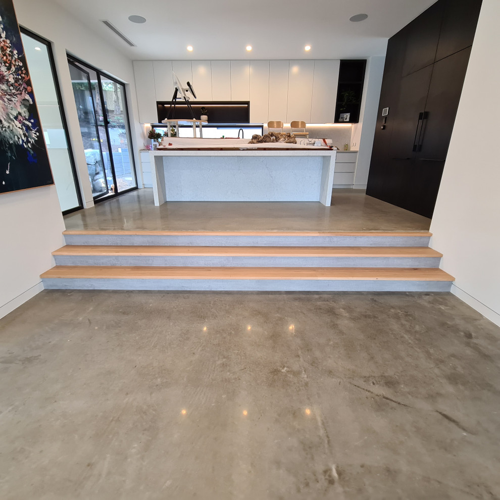 メルボルンにある高級な中くらいなコンテンポラリースタイルのおしゃれなキッチン (珪岩カウンター、白いキッチンパネル、クオーツストーンのキッチンパネル、コンクリートの床、グレーの床、白いキッチンカウンター) の写真